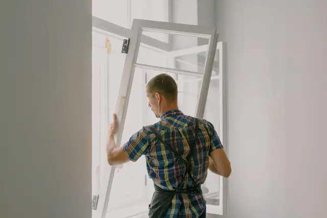 Montator poziționând o tâmplărie cu geam